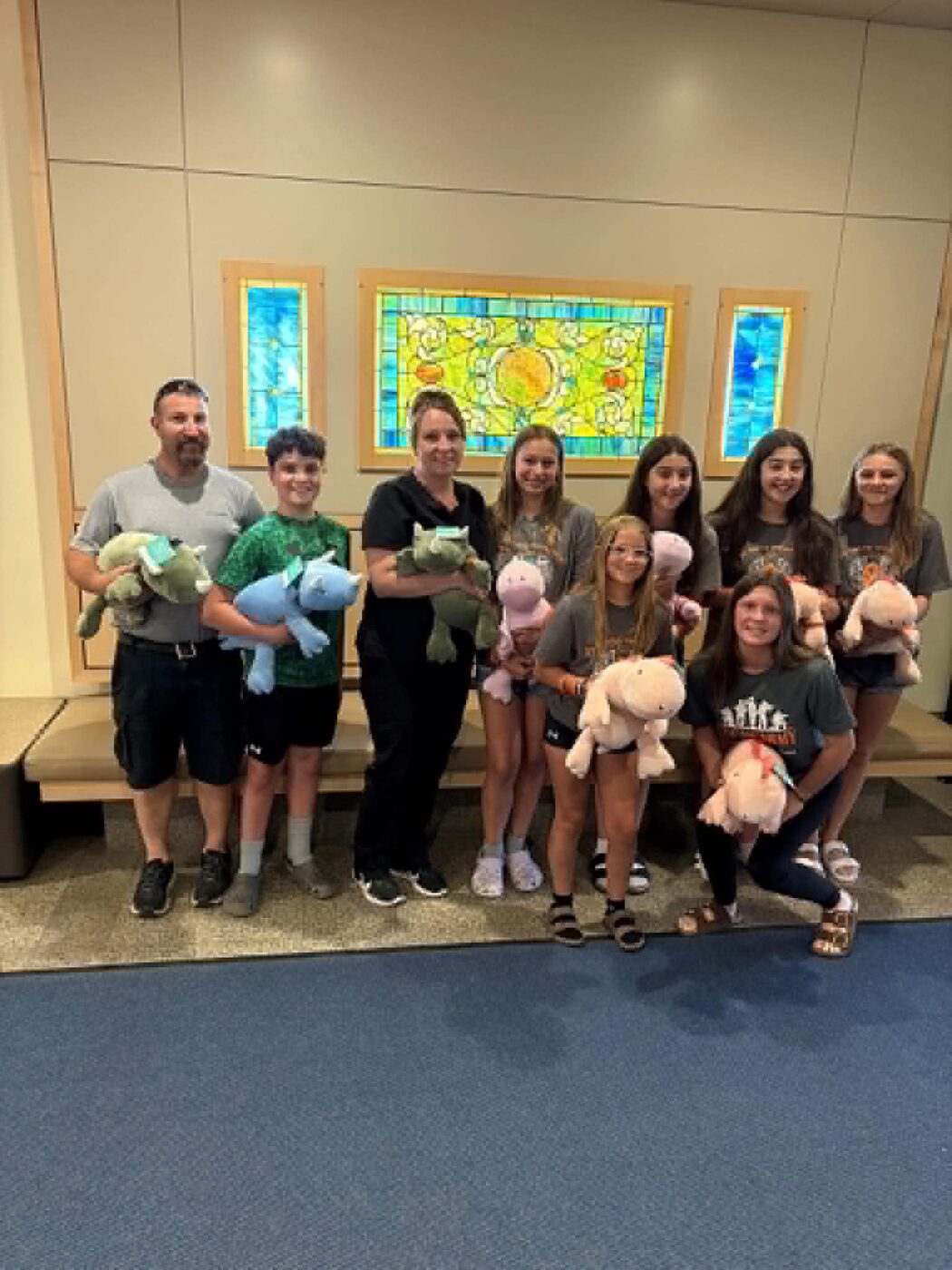 Family and volunteers holding armfuls of weighted plush dinosaurs