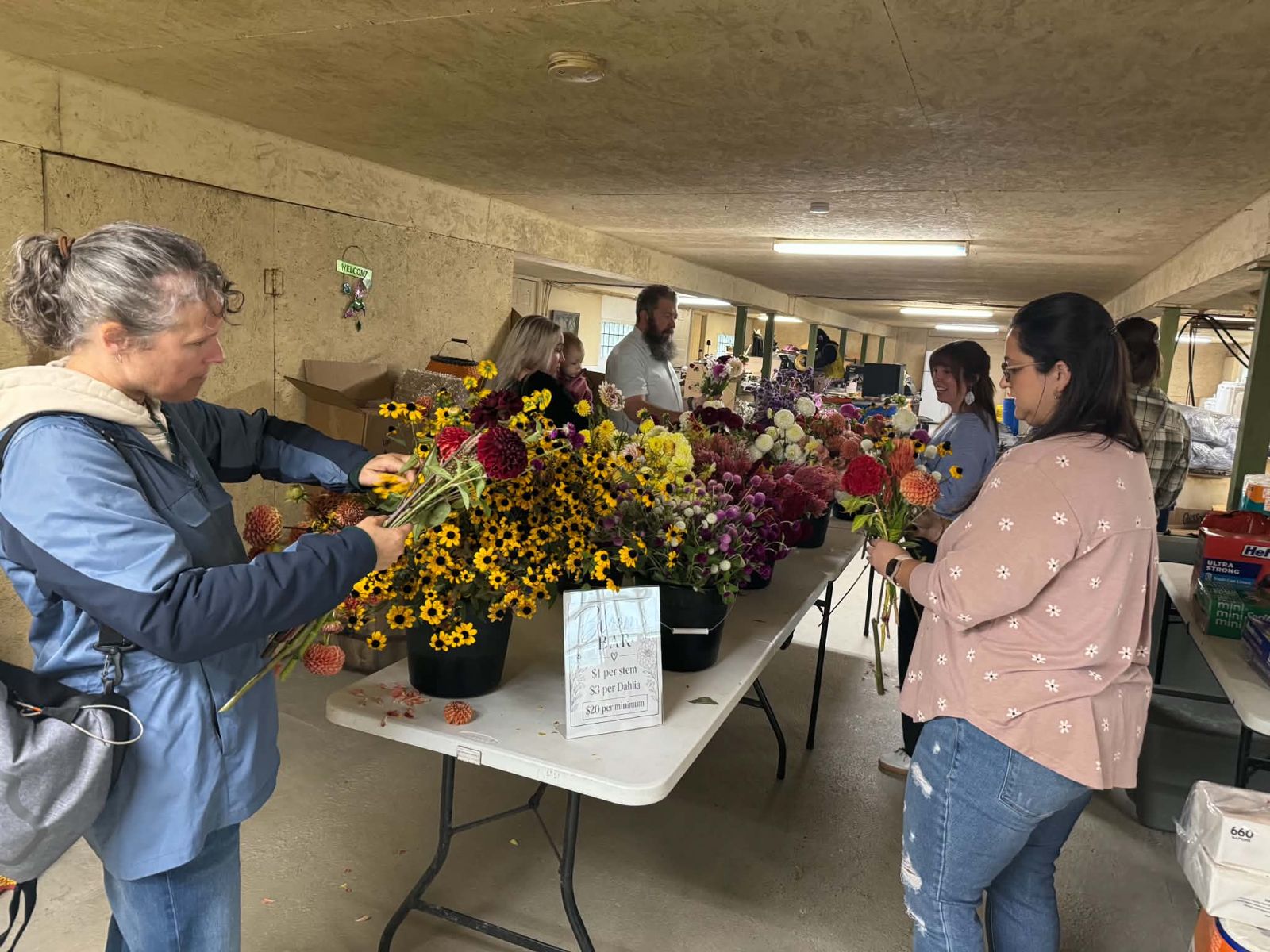 Guests picking stems from buckets of dahlias and black-eyed Susans at the Bloom Bar