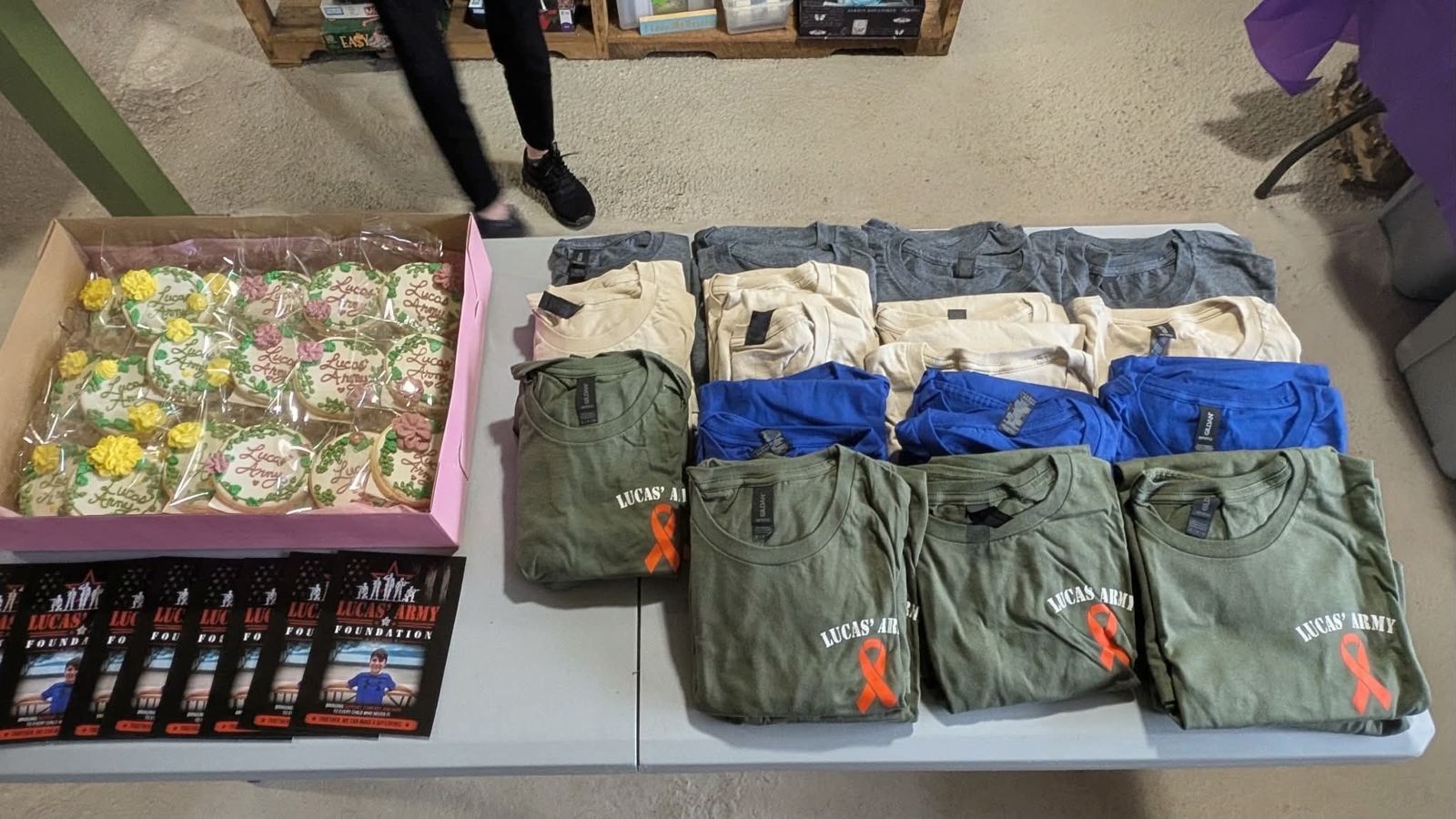 Lucas' Army shirts, decorated cookies, and flyers laid out on a table