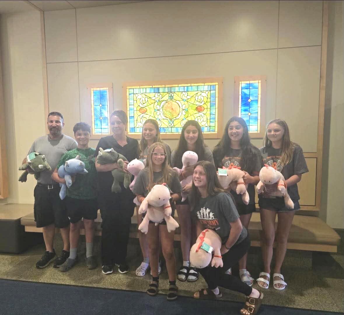Volunteers holding armfuls of weighted plush dinosaurs before a hospital delivery