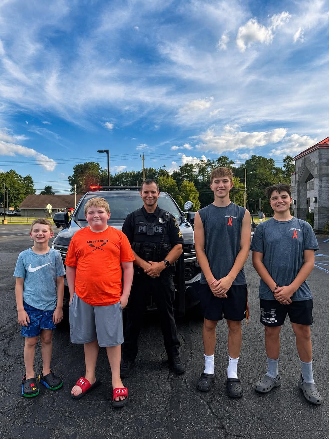 Kids in Lucas' Army shirts with a local police officer at a community fundraiser