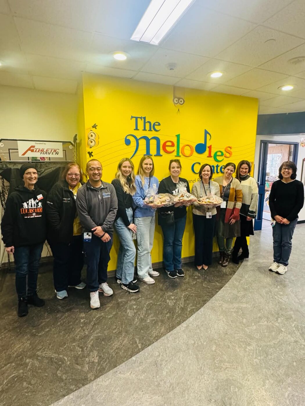 Volunteers and staff with trays of pastries at The Melodies Center