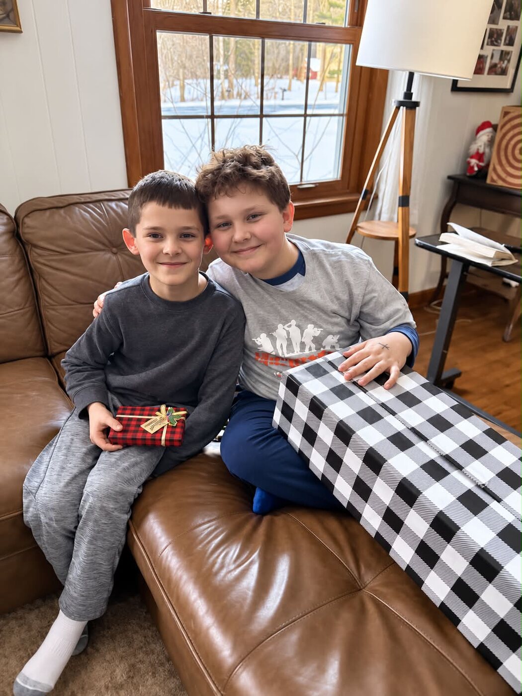 Charlie and his brother sitting together on the couch with wrapped gifts