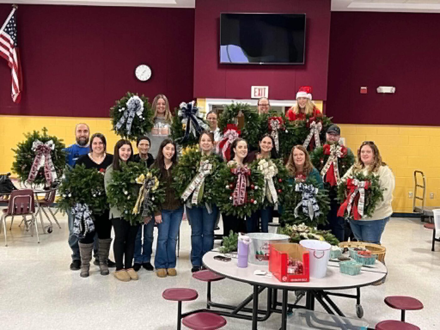 Volunteers holding handmade evergreen wreaths at the wreath workshop